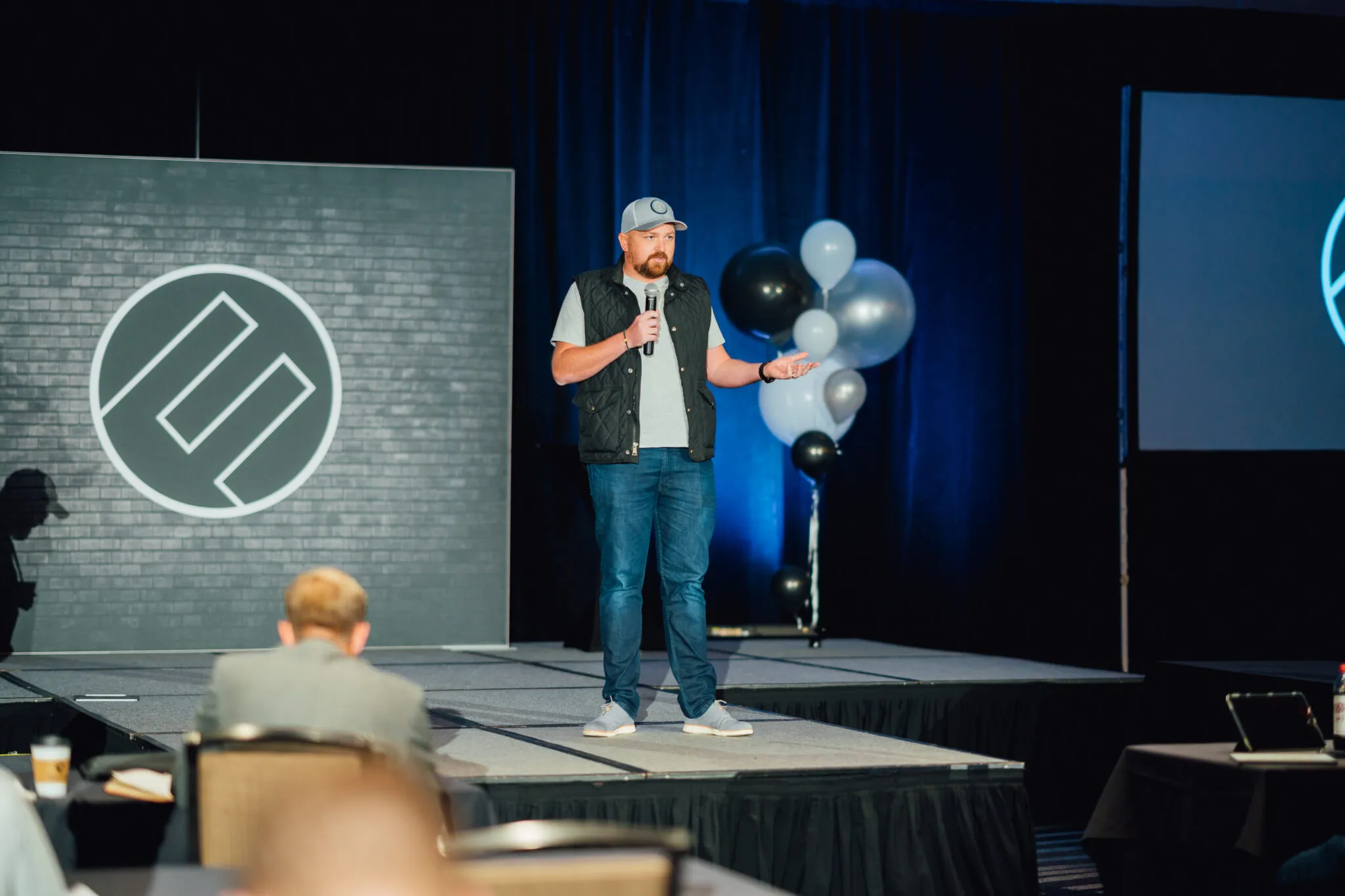 Gavin Timms on stage addressing a seated mastermind audience